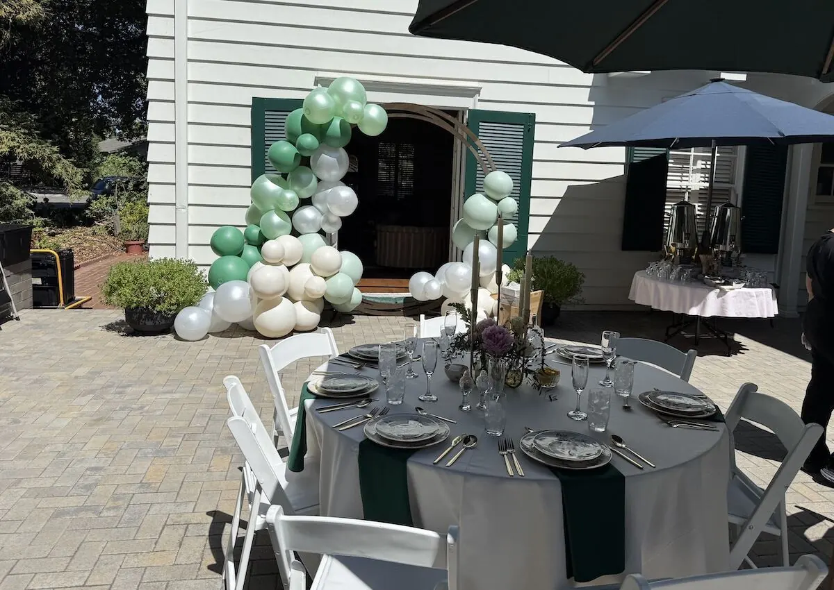 Sage and ivory balloon arch over an archway paired with a styled table — balloon and floral styling for Sunol catering and Livermore milestone parties