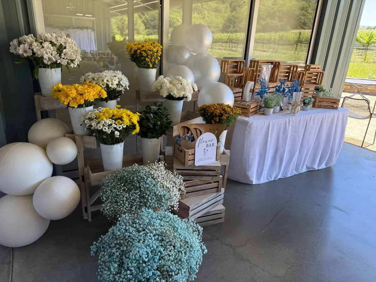 Bloom bar of buckets filled with yellow roses, daisies and baby's breath ready for guests to wrap take-home bouquets — signature bloom bar from our Livermore catering team