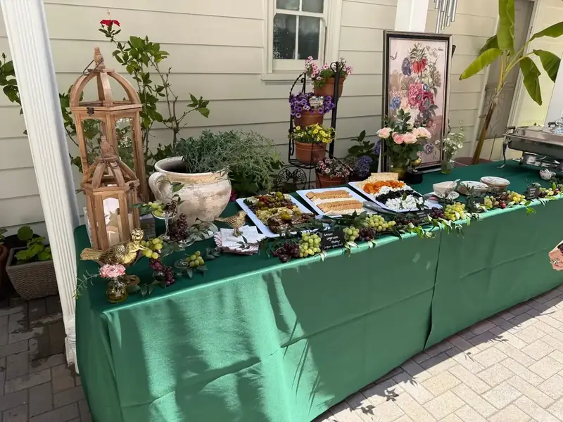 Outdoor grazing display of artisan cheeses, grapes, savory bites, greenery and rustic lanterns styled for a private party catering Sunol ranch celebration