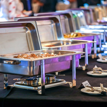 Stainless food containers on buffet table for prime rib catering